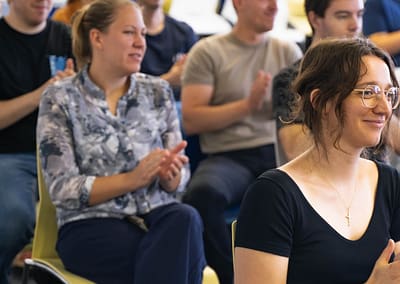 Group of participants seated at tables with laptops, collaborating and discussing during an Inno2MARE IT Bootcamp session.